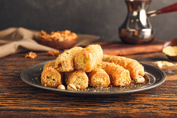 Plate with delicious baklava on wooden background