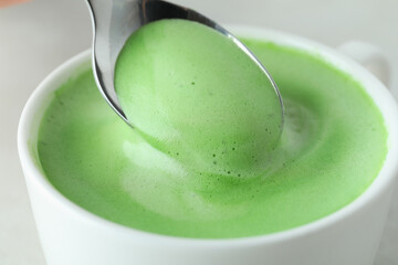 Cup and spoon with matcha latte, close up