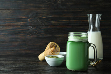 Obraz na płótnie Canvas Glass jar of matcha latte and accessories for making on wooden background