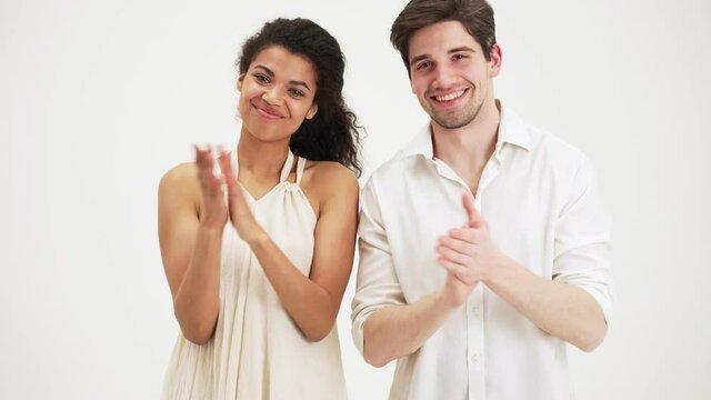 Happy couple clapping hands standing isolated over a white background in the studio