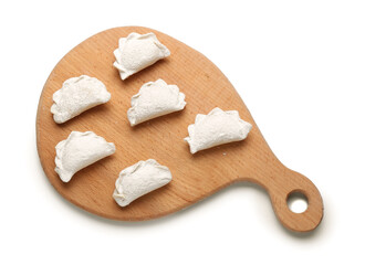 Wooden board with raw dumplings on white background