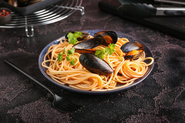 Plate of tasty Mussels Marinara with spaghetti on dark background