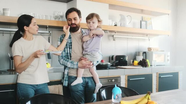 A happy family father and mother spending time with their child in the kitchen