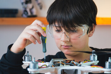 A small mechanic in goggles repairs a drone. Primary technical education.