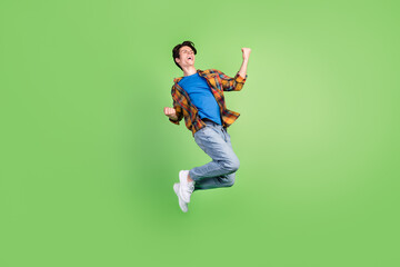 Full body profile photo of hooray brunet young guy jump wear shirt jeans sneakers isolated on green...
