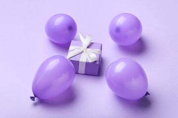 Gift box and air balloons on color background