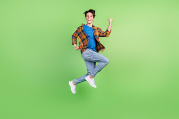 Fototapeta na wymiar Full size profile photo of funny brunet millennial guy jump yell wear shirt jeans sneakers isolated on green background