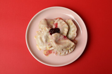 Plate with pierogi with cherry on red background