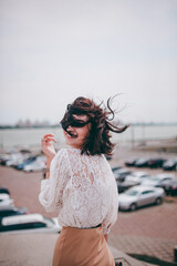 A happy girl on the river bank, standing on the bridge, smiling, a girl walks on the bridge by the river. Freedom. The wind is blowing the girl's hair.