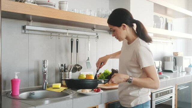 A beautiful woman cooking syrniki in the kitchen at home