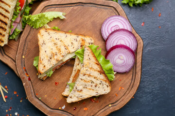 Board with tasty sandwiches on dark background