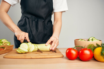 Woman in black apron cutting vegetables housework cooking