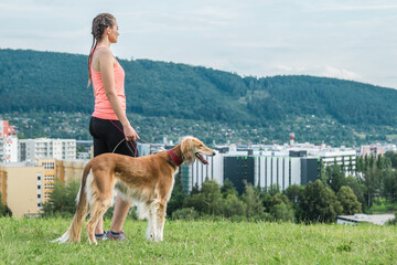 Woman and dog relaxing on field, green gras in park. Outdoor sport. Athletic young girl with his...