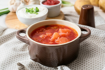 Pot of tasty borscht and ingredients on table
