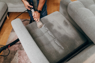 Handsome young man cleaning furniture. Process of deep furniture cleaning, removing dirt from sofa. Washing concept. - 454500566