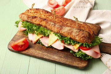 Board with tasty ciabatta sandwich on color wooden background