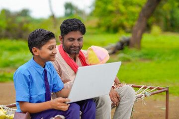 Obraz premium Education concept :cute indian school boy using laptop and giving some information to his father.