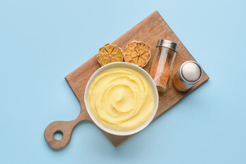 Bowl of tasty mashed potatoes with garlic on color background