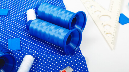 Creative sewing background, top view. Collection of various sewing tools , blue fabric, threads.