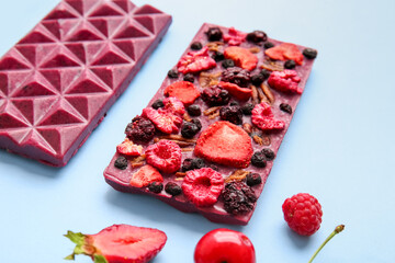 Handmade chocolate bars with fruits, berries and nuts on color background, closeup