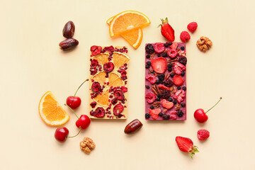 Handmade chocolate bars with fruits, berries and nuts on color background