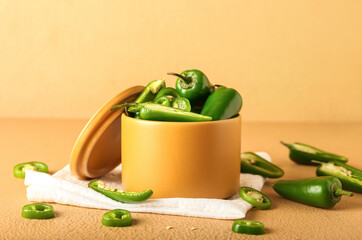 Box with cut green jalapeno peppers on color background, closeup