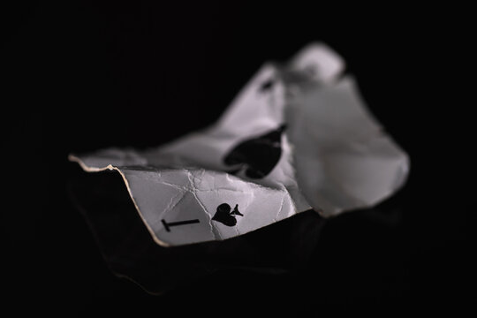 Crumpled playing card ace of spades on a black background. An image with a shallow depth of field.