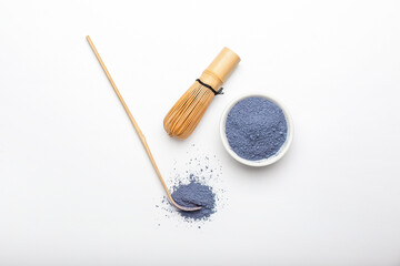 Bowl of powdered blue matcha tea, chasen and chashaku on white background