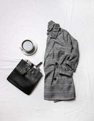 a jacket, coffee and a bag on the bed . stylish image