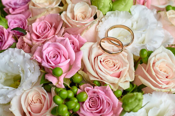 Two wedding engagement rings on a background of living roses.