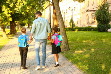 Cute little children going to school with their father