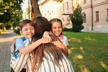 Mother saying goodbye to her little children near school