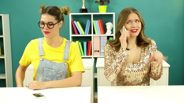 A stupid poor schoolgirl takes a picture of a rich girl in a class at school. Children's pranks while studying.