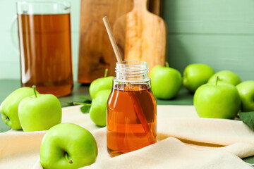 Bottle of tasty apple juice on color wooden background