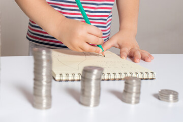 A preschooler's child records and calculates financial expenses. Literacy for children, coins.