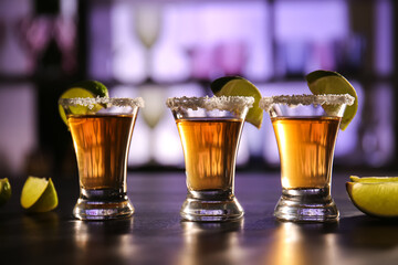 Shots of tasty tequila with lime on table in bar