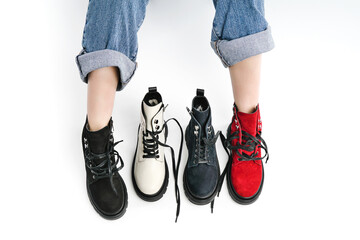 black white red leather shoes on a white background top view. woman legs in autumn fashionable boots on a white background. woman chooses shoes collection autumn spring 2022