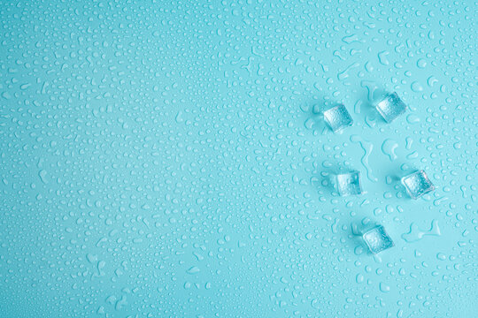 Photo of ice cubes and water drops on blue background with copy empty blank space.
