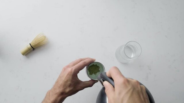 Person Pours Hot Boiled Water Into A Cup Of Green Tea Matcha. Top View