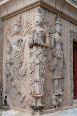 Fototapeta na wymiar Beautiful ancient stucco carving life size figures on wall of hor trai library in Wat Phra Singh buddhist temple, famous landmark of Chiang Mai, Thailand