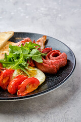 Closeup view of fried eggs with sausage, bacon, tomatoes and beans