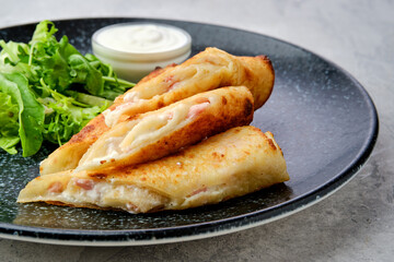 Closeup view of thin crepe stuffed with melted cheese and ham