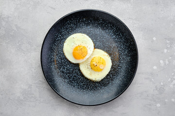 Top view of two fried eggs on a plate.