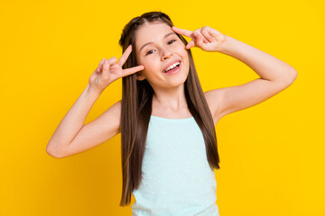 Fototapeta na wymiar Photo of cheerful cool happy small girl make v-signs smile good mood isolated on yellow color background
