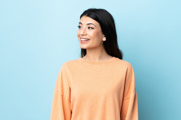 Young brunette girl over isolated blue background looking side