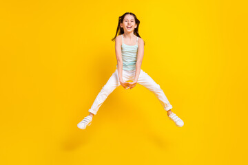 Fototapeta na wymiar Full length photo of happy cheerful little girl move travel sale jump up isolated on yellow color background