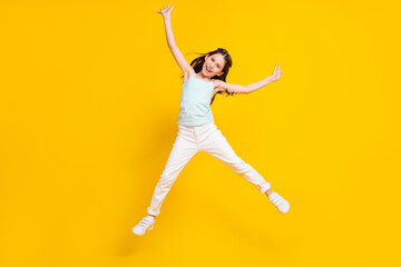 Fototapeta na wymiar Full body photo of happy positive pretty little girl good mood raise hands jump isolated on yellow color background