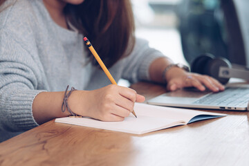 Student writing on notebook while study at home, Adult woman doing online lesson by using laptop computer, Digital technology education,Online class.