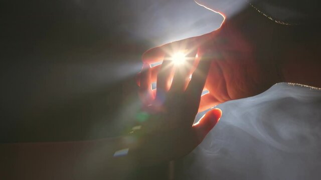 Woman hand reaches out and touches man hand receiving help, support and protection. Giving helping hand, hope and support each other concept. Backlight, rays of light break through fingers and light