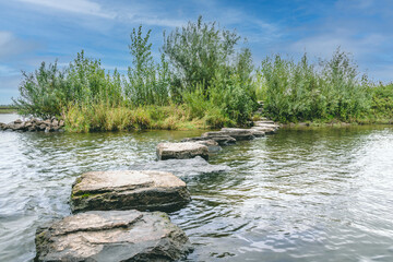 Fototapeta na wymiar stepping stones in water, maas river, den bosch, 's-hertogenbosch with blue sky